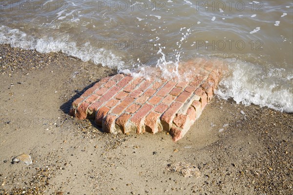 Part of red brick wall eroded and washed by waves, Happisburgh, Norfolk, England, United Kingdom, Europe