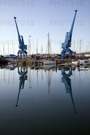 Two large blue industrial cranes reflected in water of Wet Dock marina, Ipswich, Suffolk, England, United Kingdom, Europe