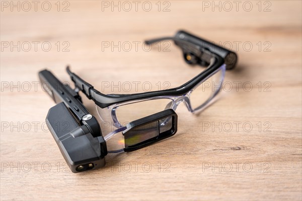 Top view on wooden table of a little portable mixed reality goggles device attached on glasses