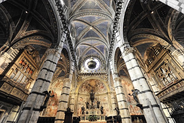 The nave of the cathedral with its black and white striped marble columns, cross and round arches, Siena, Tuscany, Italy, Europe