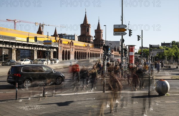 Long exposure shows underground train on the Oberbaum Bridge and people crossing a street, Berlin, 05/05/2018