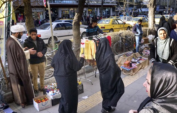 A mullah talks to a street vendor in Arak, Iran, woman wearing chadors and traditional dress on 16 March 2019. After the US withdrawal from the international nuclear deal, the country reimposes sanctions against Iran, Asia