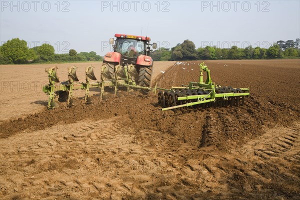 Tractor harrowing soil in field in preparation for planting, Shottisham, Suffolk, England, United Kingdom, Europe