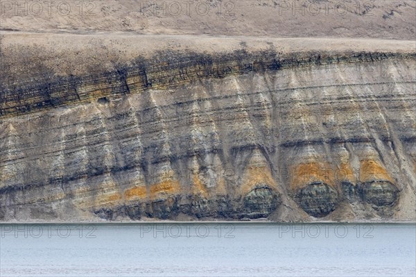 Sea cliff showing limestone and sandstone strata from the Permian period along the Hinlopen Strait, Hinlopenstretet, Spitsbergen, Svalbard, Norway, Europe