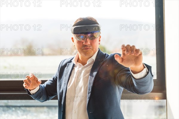 Frontal view of a businessman wearing mixed reality goggles touching interactive screen in the office