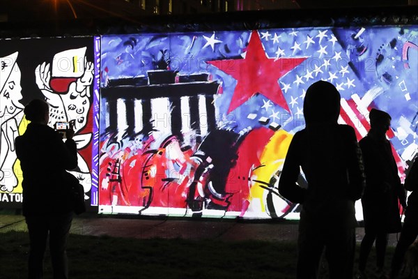 On the 30th anniversary of the fall of the Wall, 3D video projections of historical images and videos commemorate the events of the Peaceful Revolution and the opening of the Wall at original locations, such as here at the East Side Gallery, Berlin, 6 November 2019