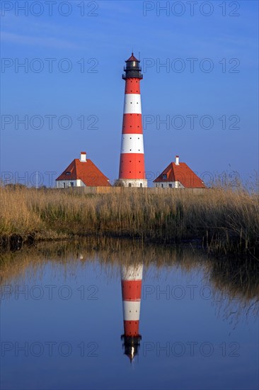 Lighthouse Westerheversand reflected in pond at Westerhever at dusk, Peninsula of Eiderstedt, Wadden Sea National Park, North Frisia, Germany, Europe