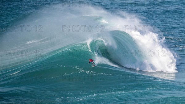 A surfer rides a crashing wave, Nazare, Portugal, Europe