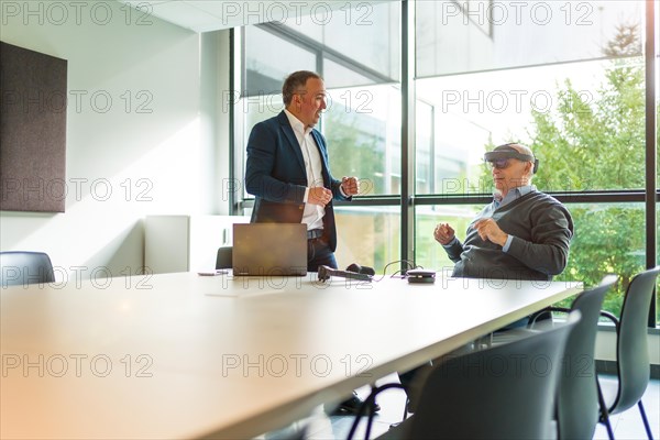 Aged businessmen reflecting the imaginary world with virtual reality in the office