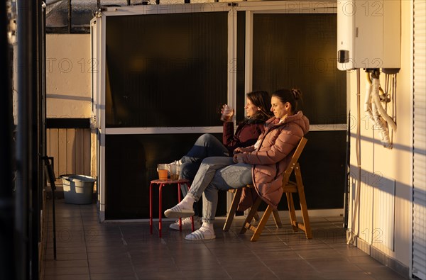 Two young woman enjoying sunset, evening light on terrace, drink, coat, Thessaloniki, Macedonia, Greece, Europe