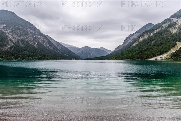 A peaceful lake surrounded by mountains under a cloudy sky, Plansee, Heiterwang, Tyrol, Austria, Europe