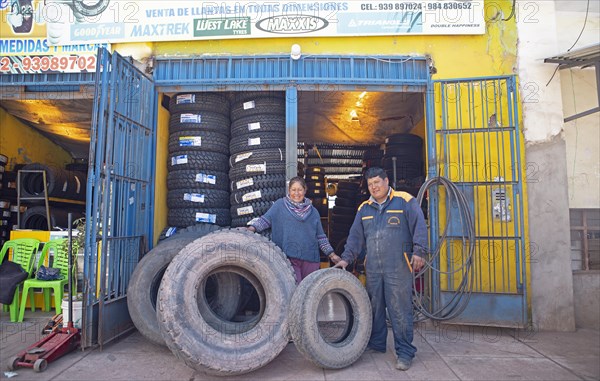Peruvian couple, 38 and 45 years old, showing tyres from their tyre workshop, Palccoyo, Checacupe district, Canchis province, Cusco region, Peru, South America