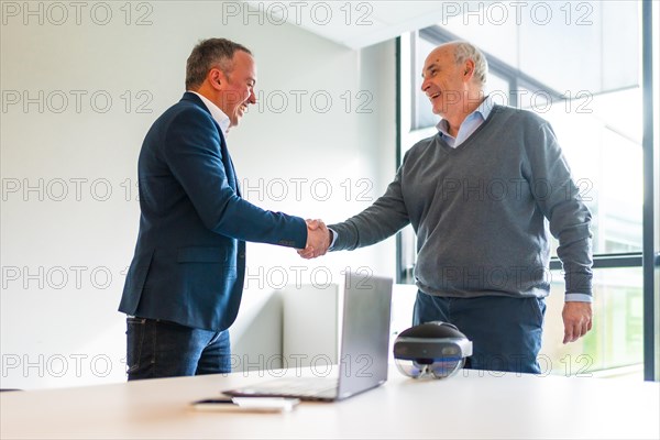 Business people closing a deal about an innovative mixed reality goggles handshaking in the office