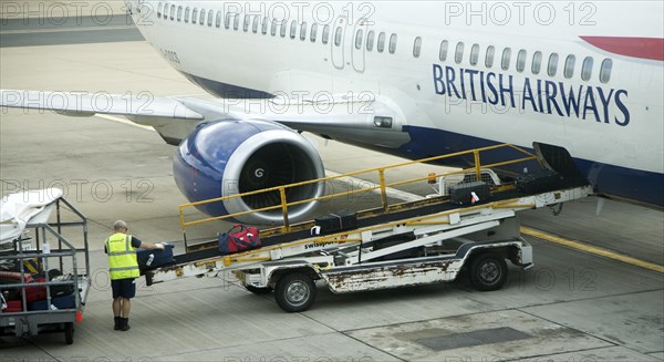 Baggage handler loading luggage onto British Airways plane at gatwick airport, London, England, United Kingdom, Europe