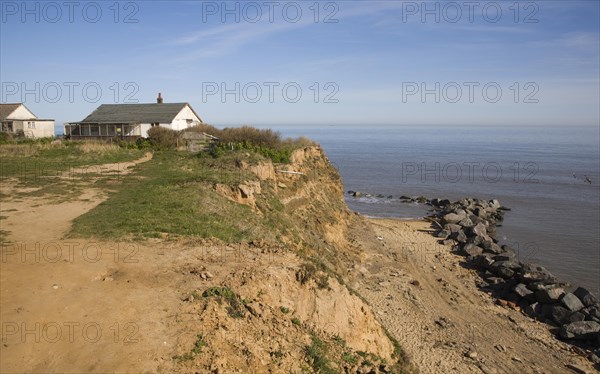 Cliff top buildings at risk of coastal erosion, Happisburgh, Norfolk, England with beach rock armour defences