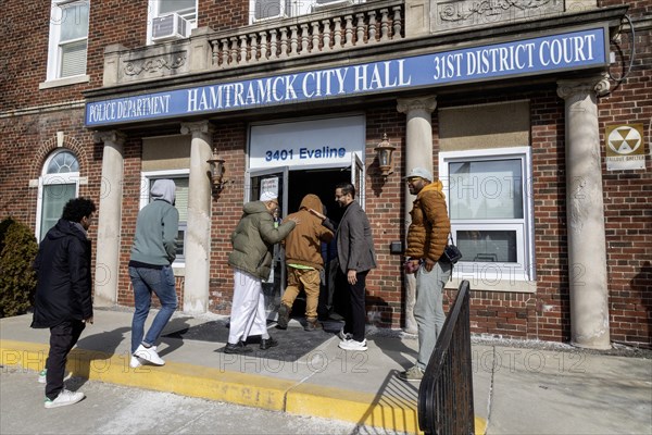 Hamtramck, Michigan USA, 25 February 2024, Abraham Aiyash (holding door), Majority Floor Leader in the Michigan House of Representatives, took residents who had not yet voted into City Hall where early voting was in progress. They had come from a rally in this heavily Arab-American city which urged a vote for uncommitted instead of for Joe Biden. Many Arab-Americans are furious about Biden's support for Israel in the Gaza war. Israel's bombing there has cost tens of thousands of Palestinian lives