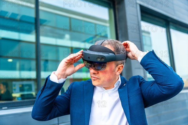 Businessman wearing augmented reality futuristic and innovative goggles outside a financial building