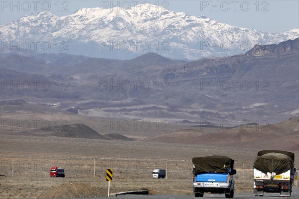 Truck on a motorway in the central desert of Iran, snow-capped mountains can be seen in the background, 13.03.2019