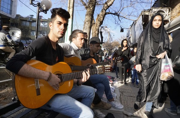 Young Iranian street musicians with guitars in Arak, Iran, woman with chador on 16 March 2019. After the withdrawal of the USA from the international nuclear agreement, the country is again imposing sanctions against Iran, Asia
