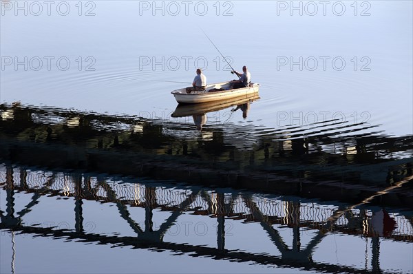 Anglers cast their rods from a boat under a bridge reflected in the Oder, Mescherin, 13 October 2018