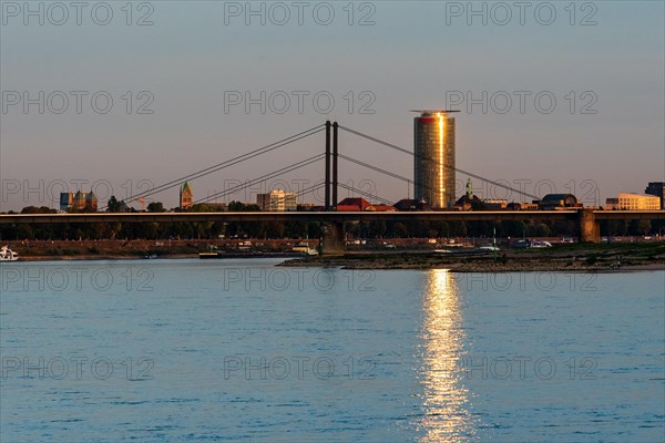 A river with a bridge and an illuminated skyscraper in the background at sunset, Theodor-Heuss-Bruecke, Duesseldorf, North Rhine-Westphalia