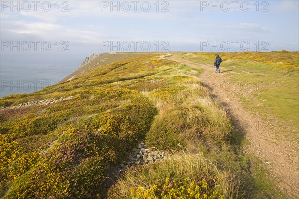Woman wearing kagoule walking along the South West coast path at St Agnes head, Cornwall, England, United Kingdom, Europe