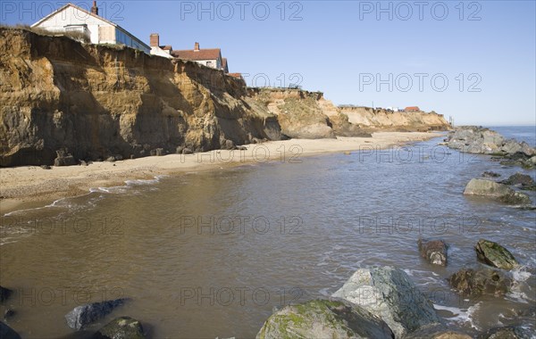 Cliff top buildings at risk of coastal erosion, Happisburgh, Norfolk, England rock armour boulders used as defence