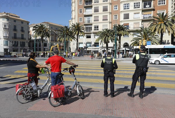 Spanish police officers stand next to tourists with bicycles in the city centre of Malaga, 11.02. 2019