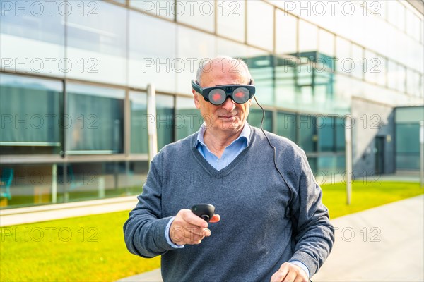 Smiling elder businessman using an augmented reality device outside the financial building