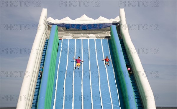 Children playing on giant inflated slide seaside attraction, Great Yarmouth, Norfolk, England, United Kingdom, Europe