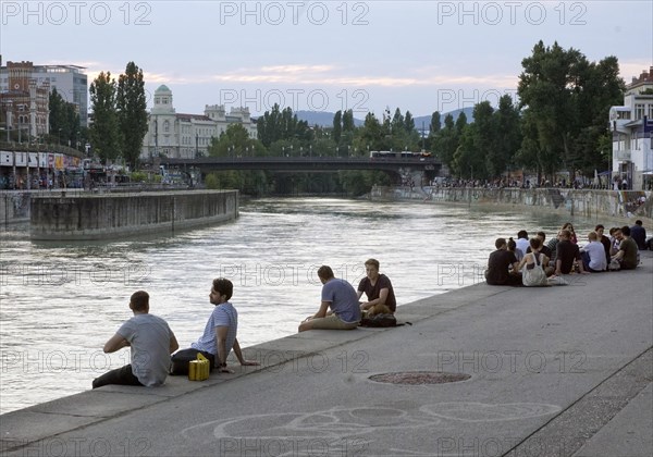 People relaxing in summer temperatures on the banks of the Danube Canal in Vienna, 19 July 2019