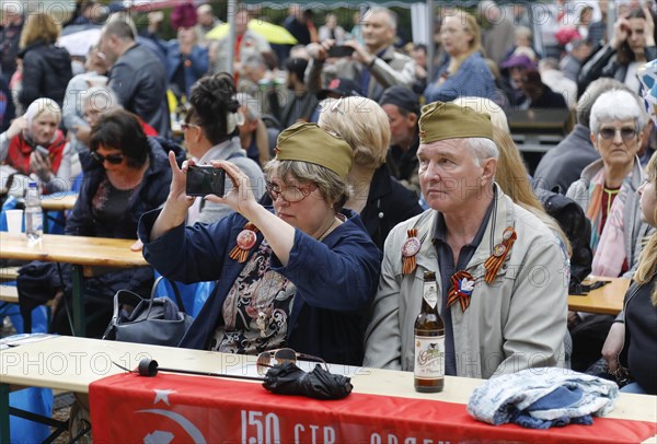 A man and a woman wear caps from Russian uniforms on the 74th anniversary of the victory of Russia over Germany, during a music concert at the Russian memorial in Treptower Park in Berlin, 09.05.2019