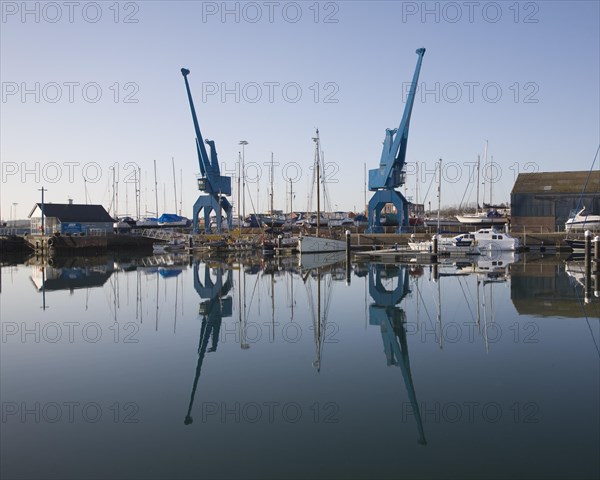 Two large blue industrial cranes reflected in water of Wet Dock marina, Ipswich, Suffolk, England, United Kingdom, Europe