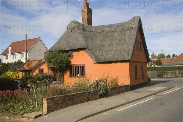 Orange coloured historic thatched building in Hollesley village, Suffolk, England, United Kingdom, Europe