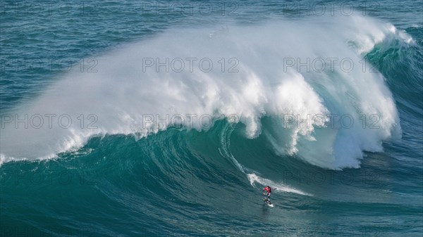 A surfer rides a crashing wave, Nazare, Portugal, Europe