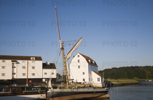 Historic sailing barge and whitewashed buildings of the Tide Mill on the River Deben, Woodbridge, Suffolk, England, UK