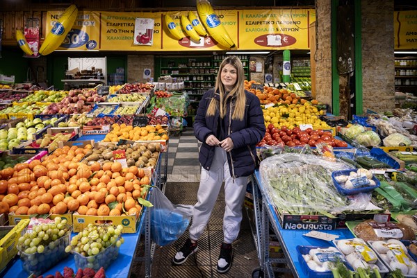 Trader, fruit seller, young woman, posing proudly in front of her market stall, display of fresh fruit, oranges, pineapples, bananas, kiwi, apples, plums, fruit seller, food, Kapani market, Vlali, Thessaloniki, Macedonia, Greece, Europe