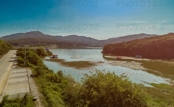 A scenic landscape depicting a serene river winding through mountains under a blue sky, in South Korea