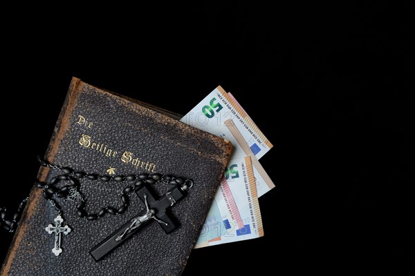 Bible, crucifix and banknotes, church and money, church tax