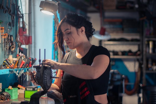 A craftswoman is carefully engaged in repair work, surrounded by tools in her occupation, a complete tool panel in background with bokeh effect, traditional male jobs by Mixed-race latino woman