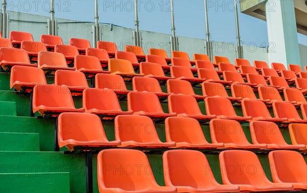 Rows of empty orange seats ascending green steps at a stadium, in South Korea