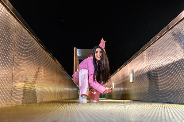 Low angle view portrait of an active free style dancer performing sitting on a bridge at night