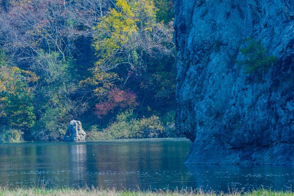 Autumnal river scene with cliff face and colorful trees, in South Korea