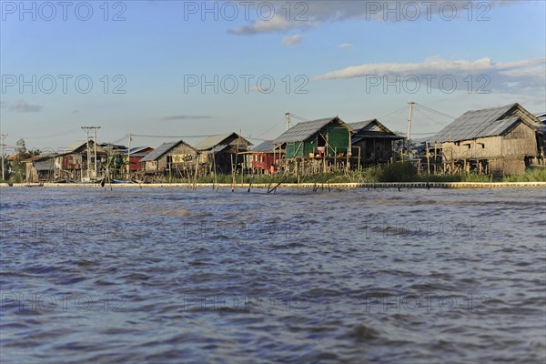Stilt houses on the edge of a river with golden evening light, Inle Lake, Myanmar, Asia