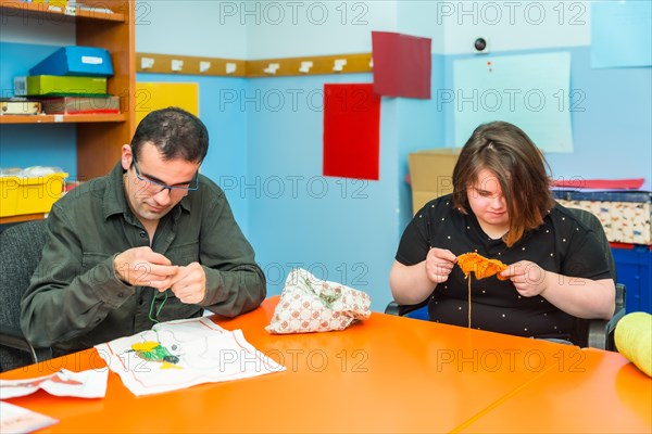 People with intellectual disabilities knitting clothes with wool in a day care center