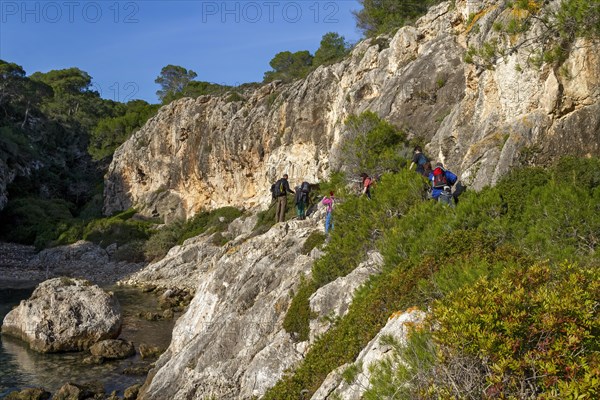 Group of hikers traversing a rocky nature trail in a forested area, Coastal Hiking tour in the south of Mallorca