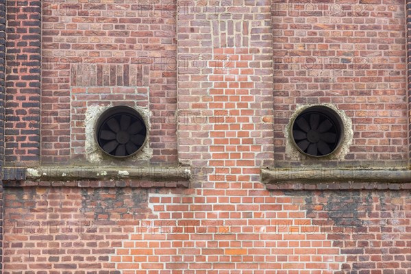 Old brick facade with round ventilation openings in the wall