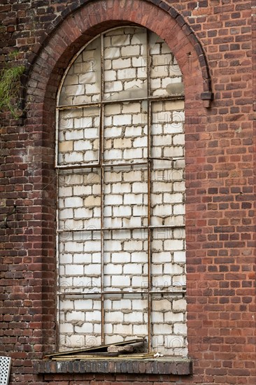 Arched brick window that has been bricked up and shows patina