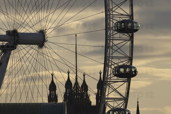 London Eye or Millennium Wheel tourist observation wheel close up of pods and spokes at sunset with the Houses of Parliment in the background, City of London, England, United Kingdom, Europe