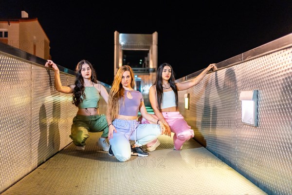 Frontal portrait of an alternative group of young and cool hip hop dancers posing on a bridge at night